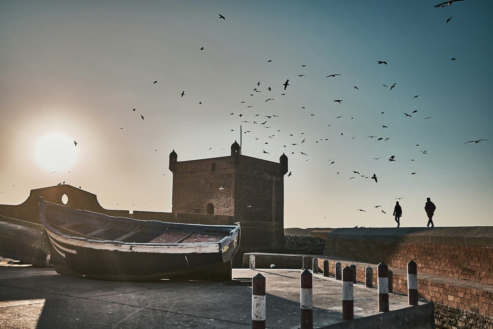 the Sqala sea fortress of Essaouira silhouetted against a golden sunset with seabirds wheeling overhead
