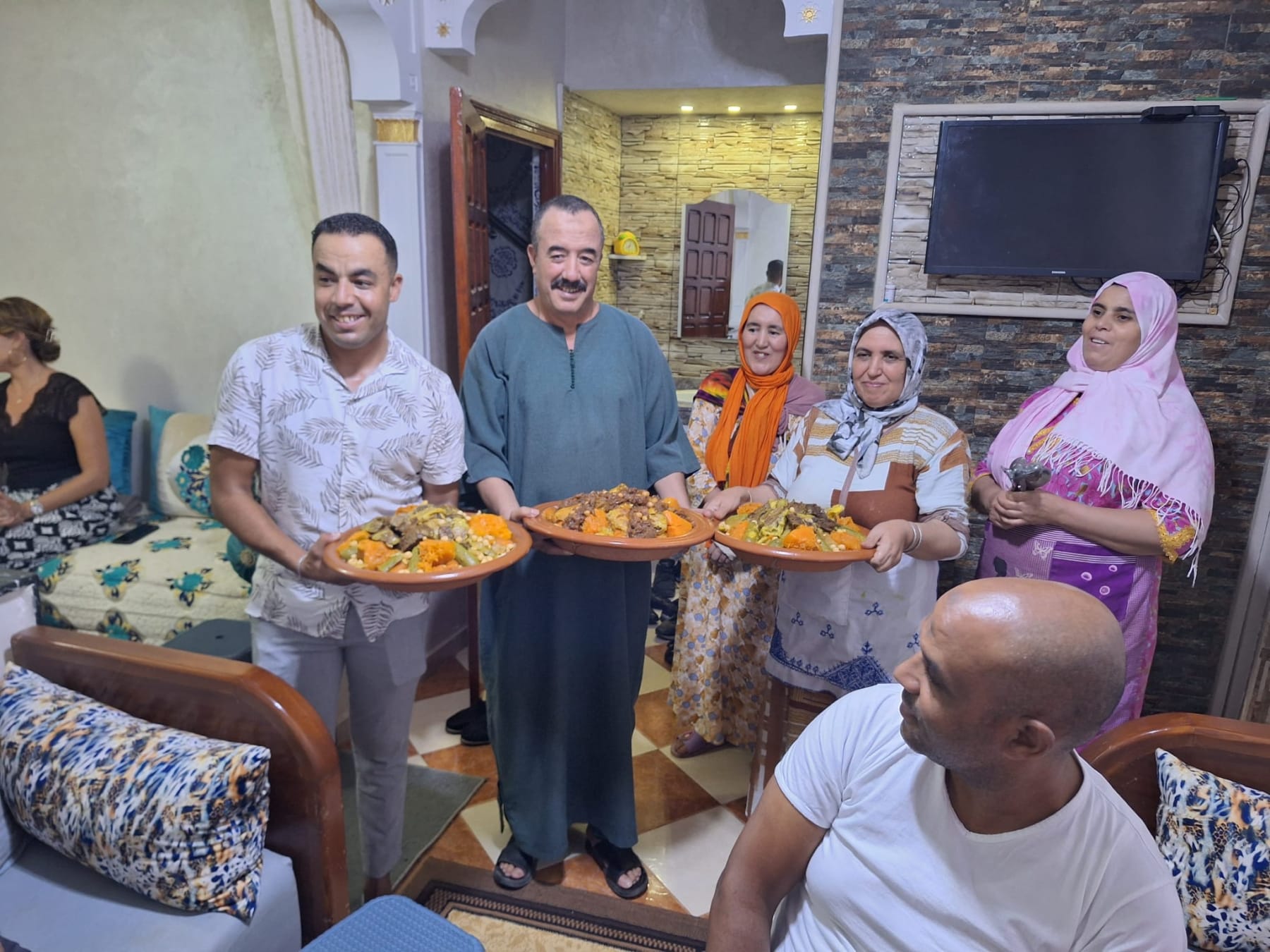 Hasy and a Moroccan family presenting home-cooked couscous to guests gathered in their home