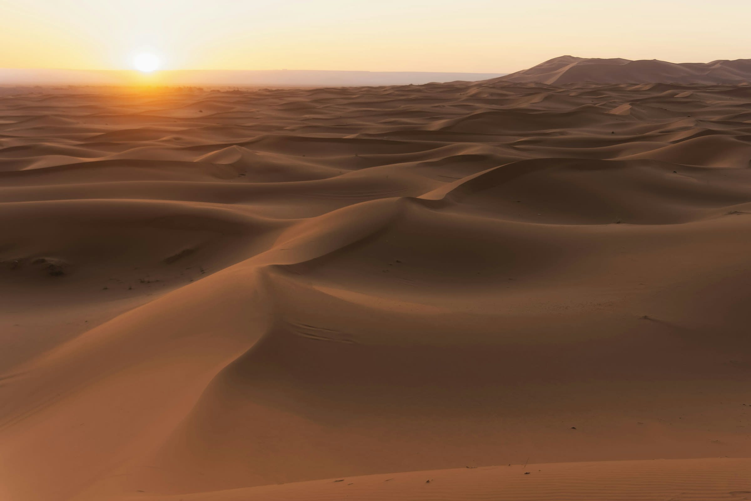 golden sun setting over the Sahara dunes near Merzouga, Morocco